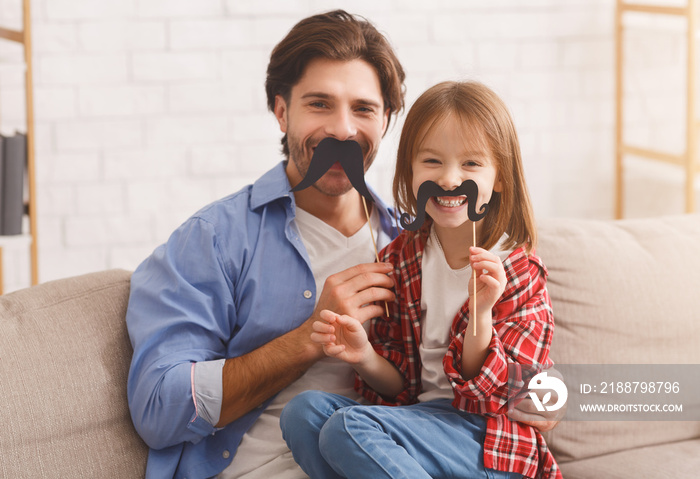 Beautiful funny girl and daddy have mustaches on sticks