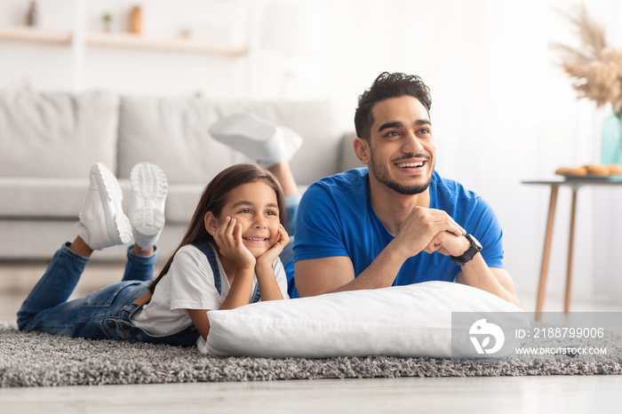 Happy young family watching television lying on floor