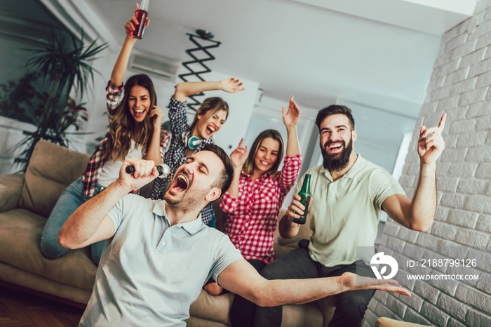 Group of friends playing karaoke at home. Concept about friendship, home entertainment and people