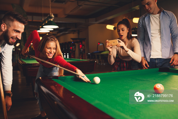 Group of friends play billiards at night out