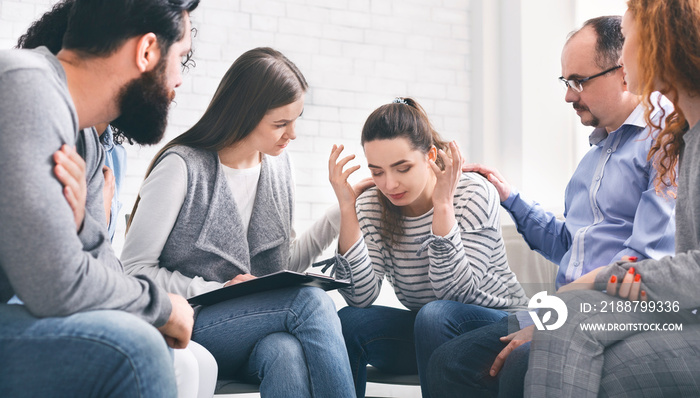 Depressed woman sharing her problems with group on therapy session