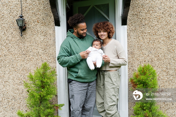 Parents holding baby daughter in front of home