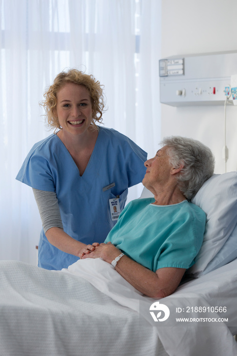 Portrait happy female nurse caring for senior patient in hospital room