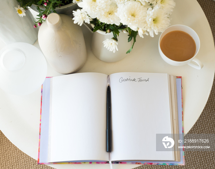桌上有茶和花的钢笔的空白感恩日记的高角度视图（选择性聚焦）
