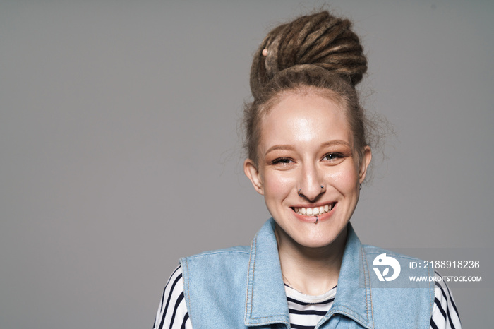 Image of extraordinary girl with face piercing and dreadlocks smiling