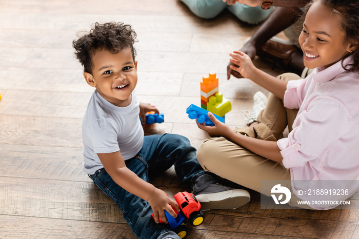 high angle view of african american brother and sister playing with toy truck and building blocks on