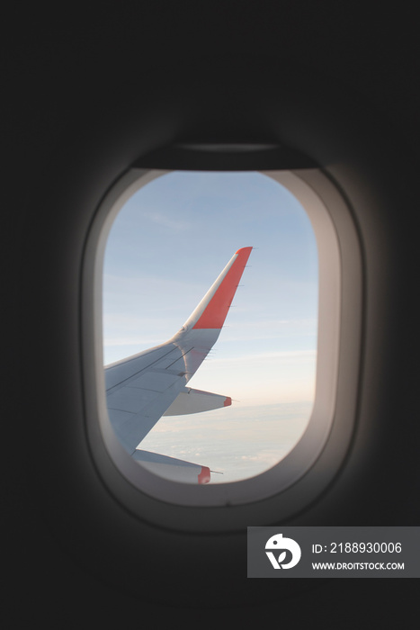 从飞机窗户里看。看着外面的机翼，看到云朵和蓝天。