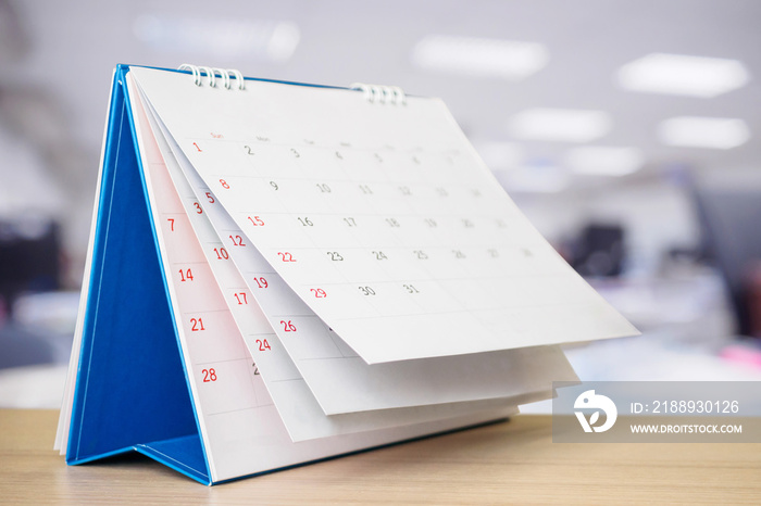 Calendar page flipping sheet on table with blurred office interior background business schedule plan