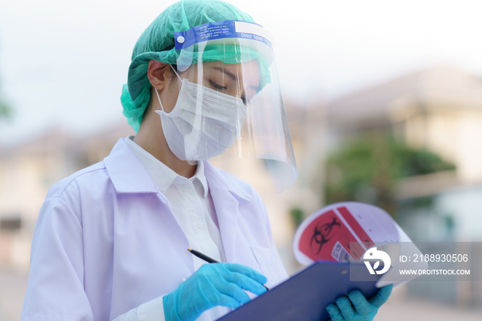 Woman doctor, holding patient report form folder, outdoor portrait, Coronavirus COVID-19 pandemic. (