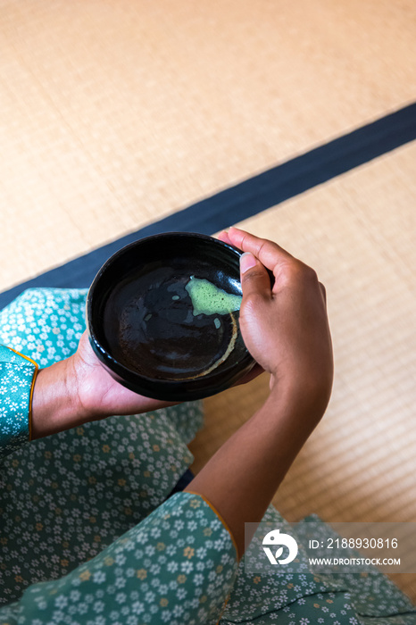 日本传统茶中喝抹茶后，黑人妇女双手转动茶碗