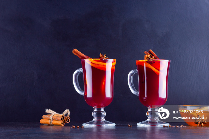 Glass of hot mulled wine with spices on dark background. Christmas mulled wine with orange, star ani