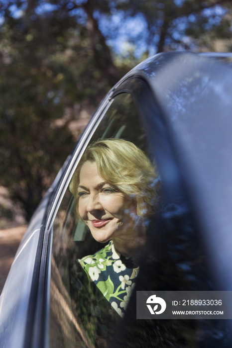 Serene senior woman looking out sunny car window