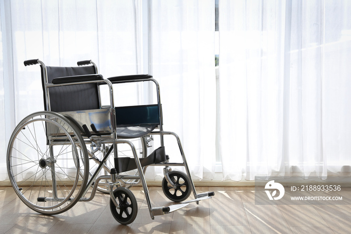 A wheelchair in a room with white curtains.