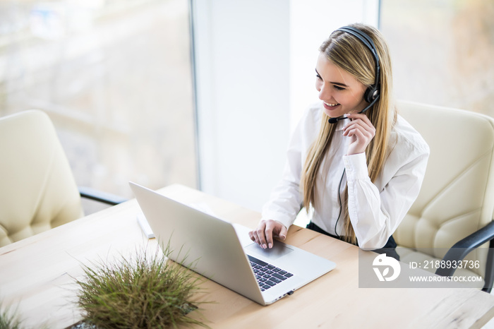 Portrait of happy smiling female customer support phone operator at workplace.