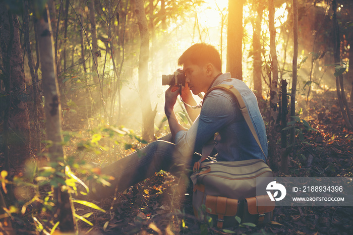 Young Man traveler with retro photo camera walking in forest Fas