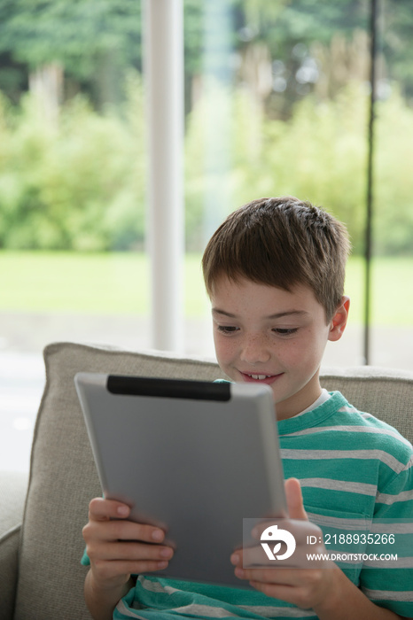 Boy using digital tablet on sofa