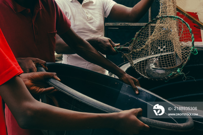 African father extracting catfish from home fish pond