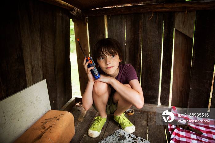 Boy playing with two way radio in wooden shed