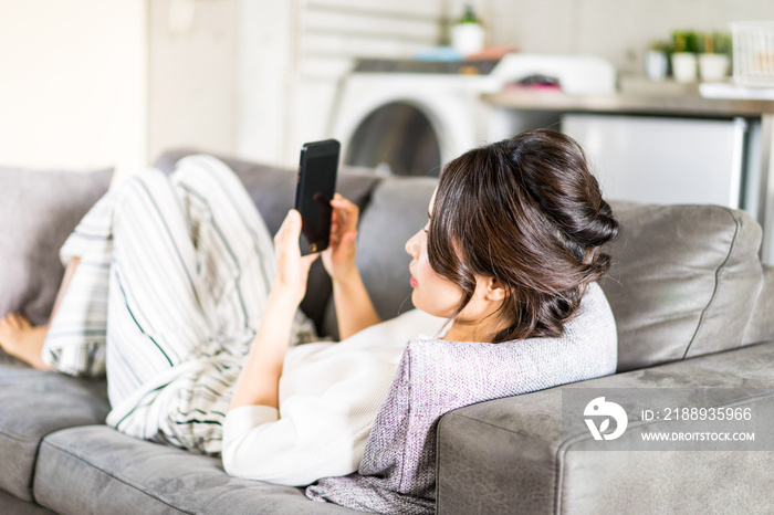 部屋でスマホを使う若い女性