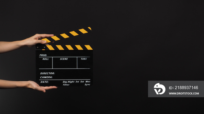 Hand is holding Black clapper board or movie slate use in video production and movie industry on bla
