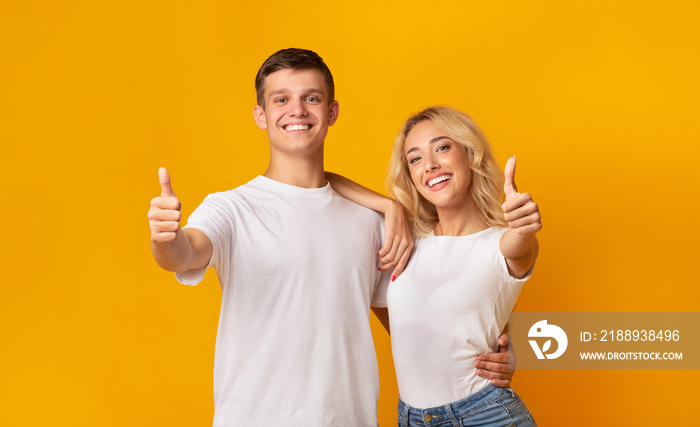 Happy young couple showing thumbs up gesture, recommending something