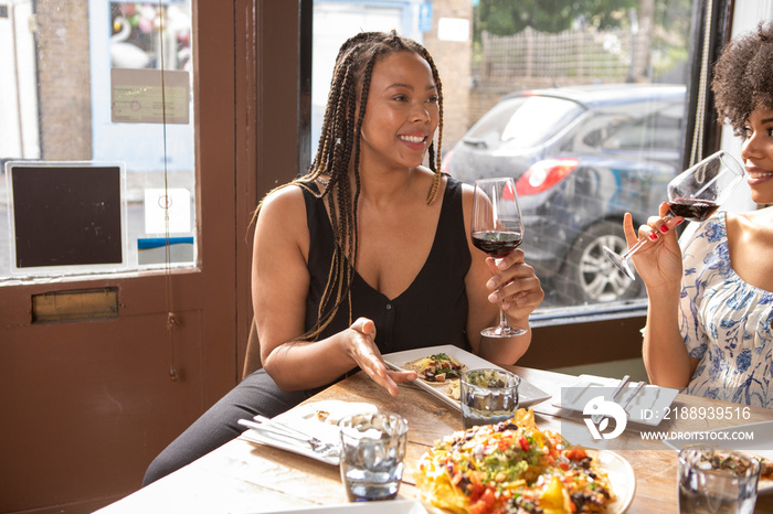 �UK, London, Smiling friends enjoying Mexican food at restaurant table