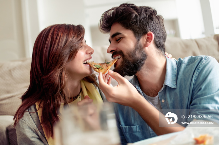 Young couple eating pizza at home