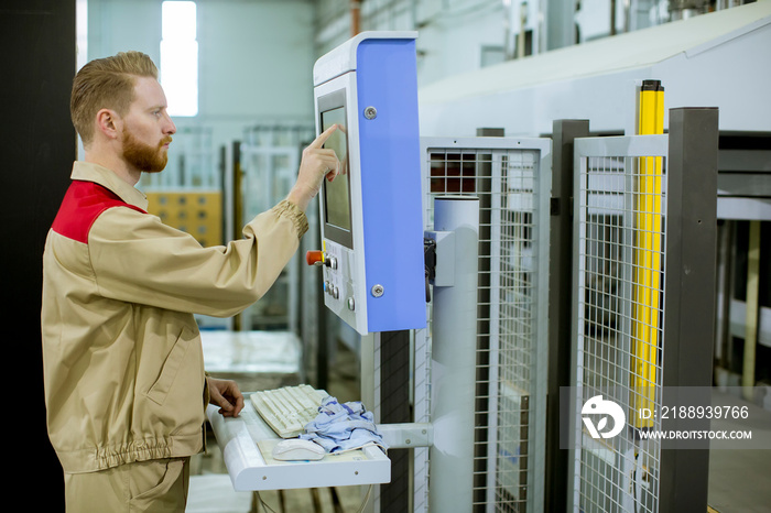 Male operator presses the button on the control panel at the control devices in the furniture produc