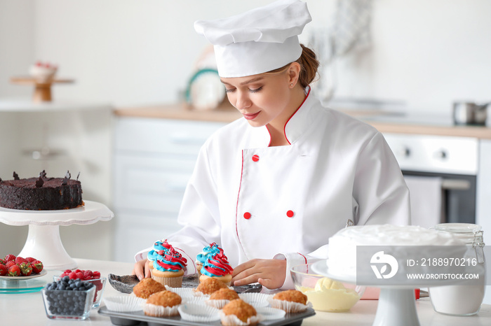 Female confectioner cooking tasty cupcakes in kitchen