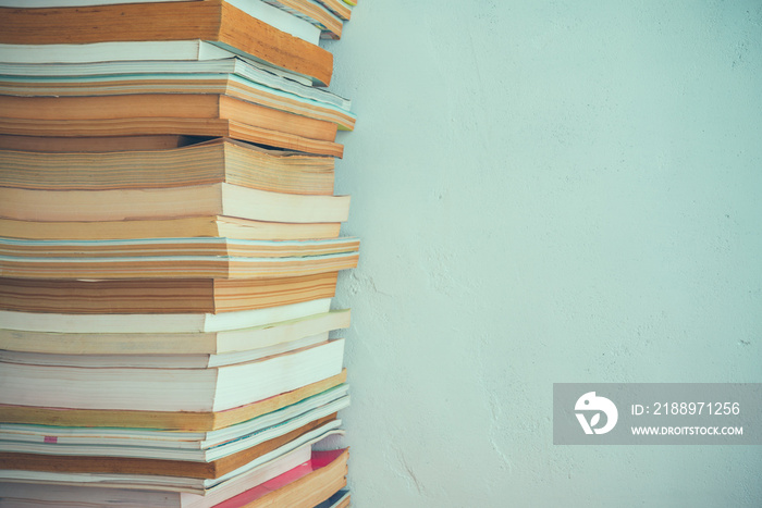 Stack of many old books on shelf in book store or library room with white wall background. Knowledge