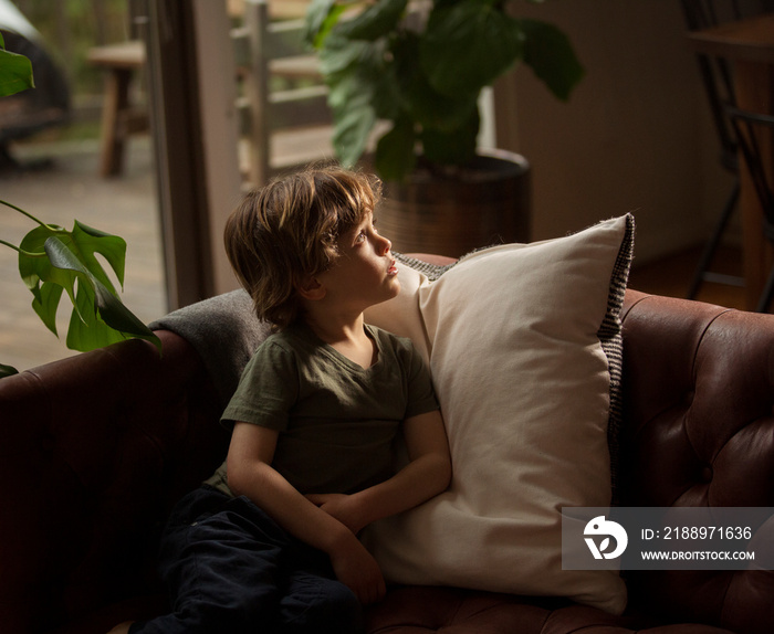 Thoughtful boy relaxing on sofa at home