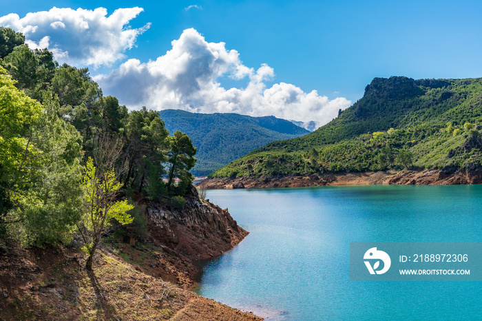 Vista del embalse del Tranco en Cazorla, rodeado de montañas boscosas en un perfecto día soleado.