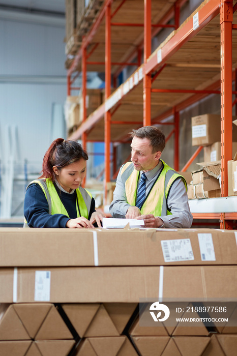 Manager training female factory worker in factory warehouse packing