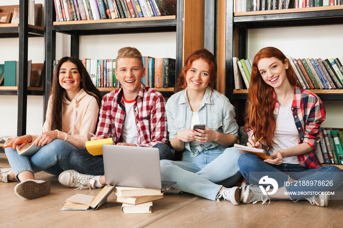 Group of smiling teenagers doing homework