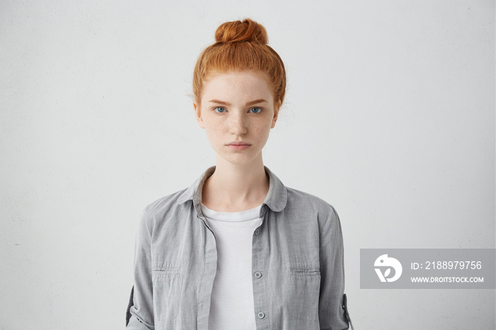 Waist up portrait of beautiful European 20 y.o. woman with freckles and hair knot posing isolated ag