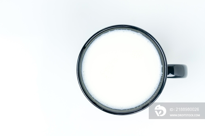 Top view of milk in black ceramic cup on white  background with copy space.