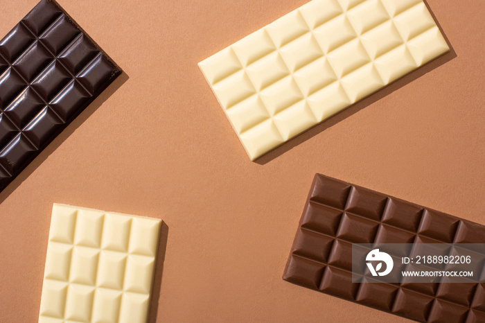 top view of delicious whole milk, white and dark chocolate bars on dark background