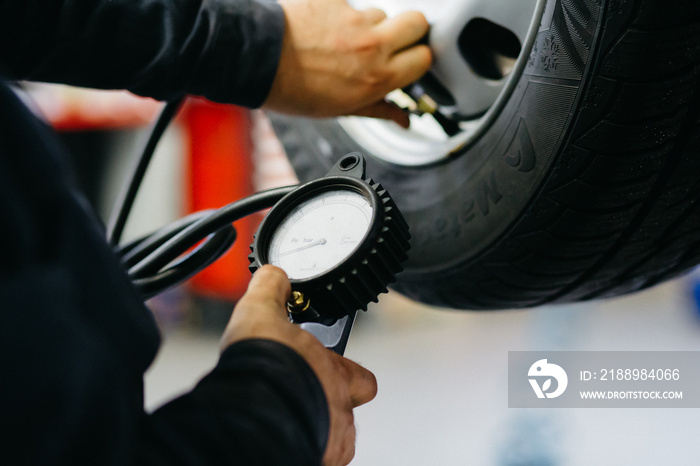 auto mechanic checks tire pressure