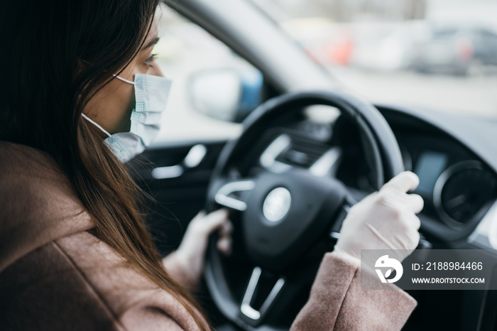 Young woman in a mask and gloves driving a car.