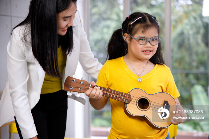 Asian teacher teach ukulele to girl with Downs syndrome.
