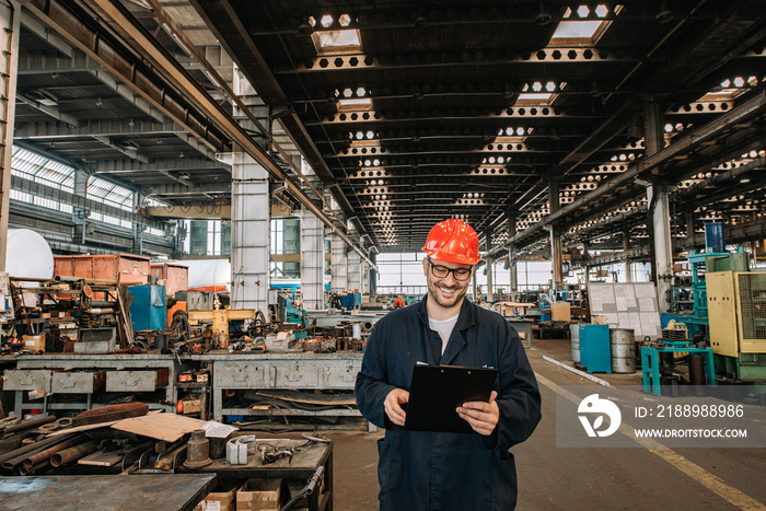 Portrait of a smiling mechanic at large metal industry hall.