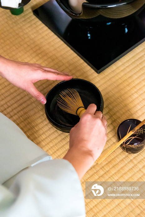 日本女人，茶艺大师，Sen Rikyu，在日本特拉华州用手净化一个竹抹茶搅拌器