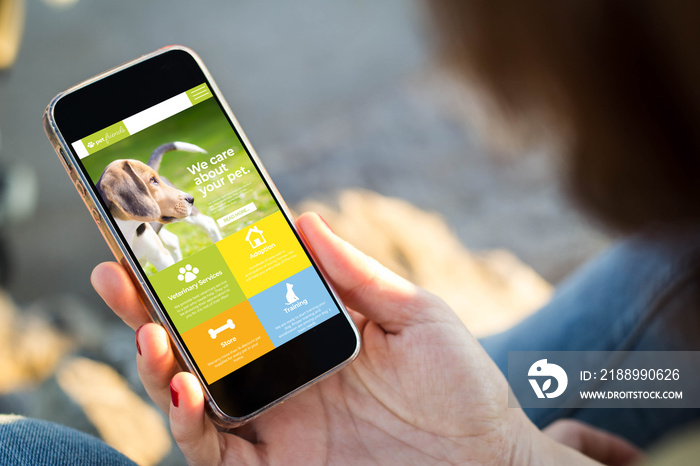 woman sitting in the street holding her smartphone showing pet website