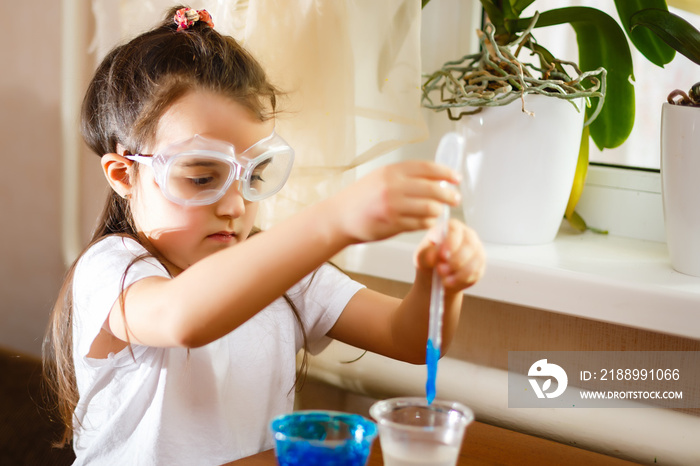 Little girl experimenting in elementary science class with protective gloves and glasses