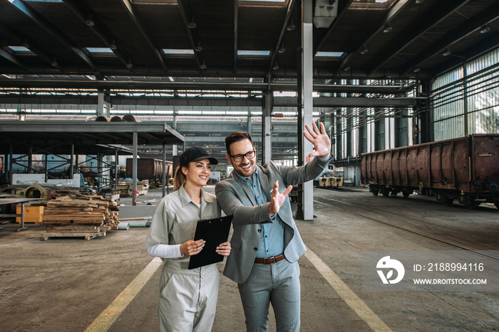 Investor talking to a female employee at large train repair station.