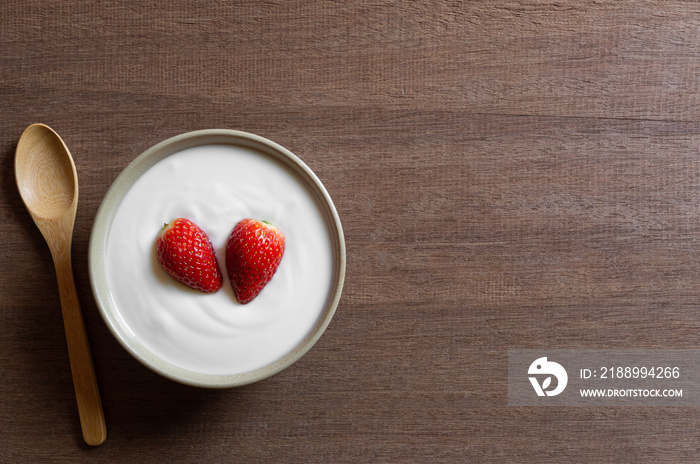 top view of natural yogurt with strawberry in a ceramic bowl on wooden table, copy space. healthy fo