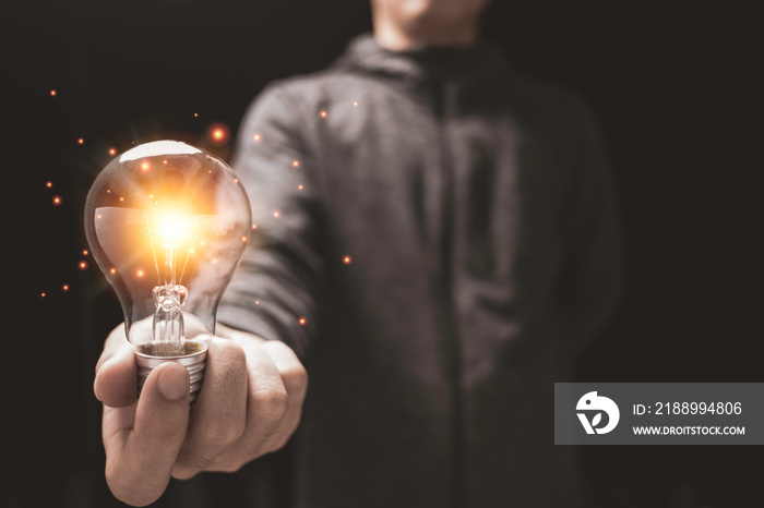 Businessman holding glowing lightbulb with orange light . Creative new business idea concept.