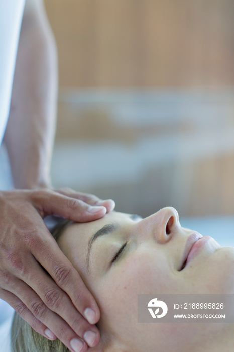 Serene young woman receiving head massage in spa