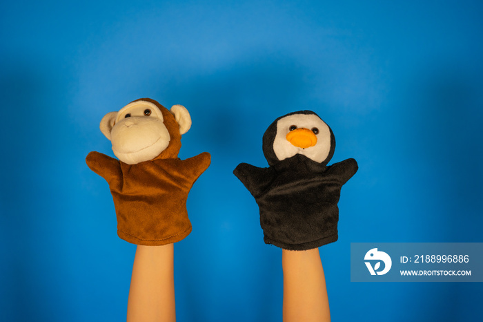 Soft puppet toys on hands on blue background. Concept of puppet show. Close-up of hands with puppet 