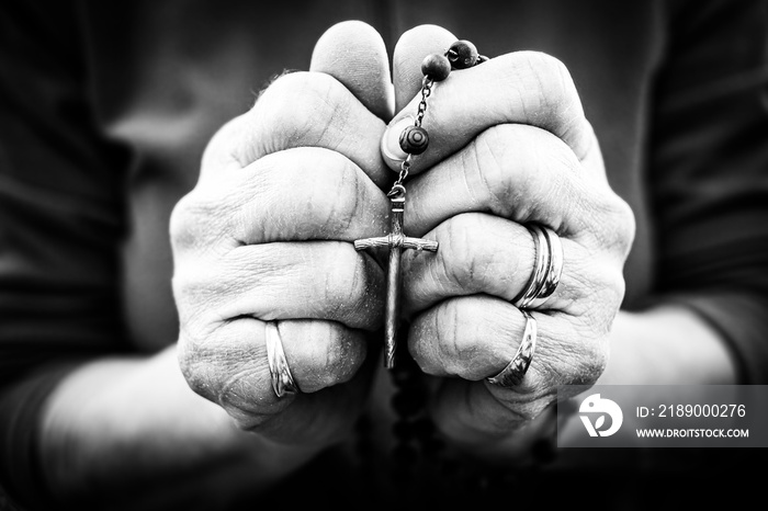 Old wrinkled woman hands holding a rosary. Closeup of christian  woman hands holding rosary while pr